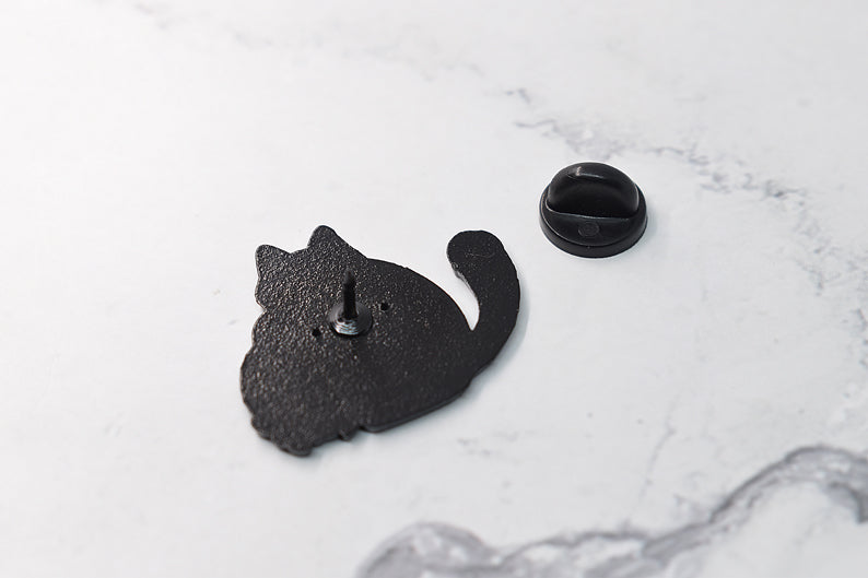 Enamel pin with black cat holding a skull